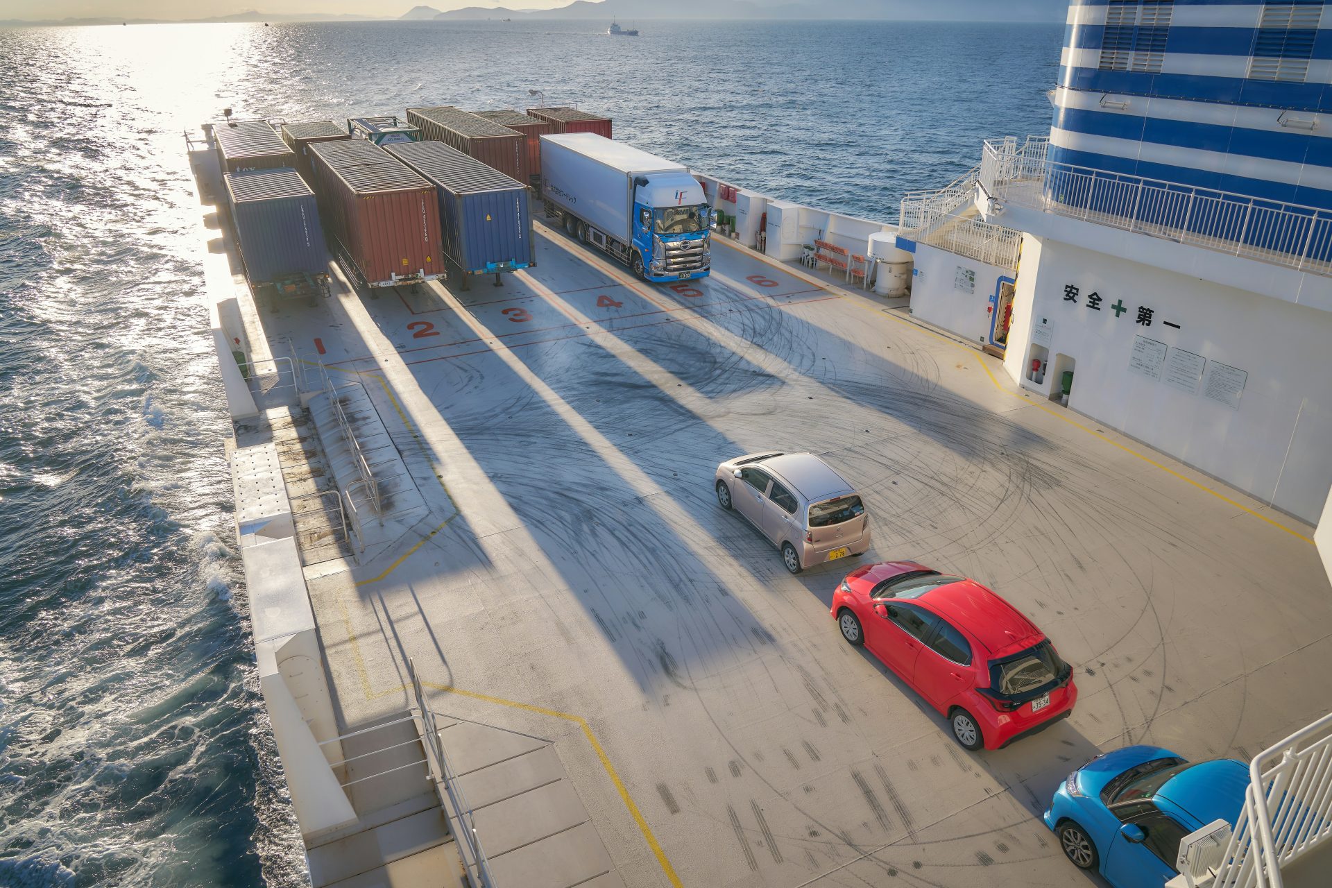 A red car is parked on the side of a ferry
